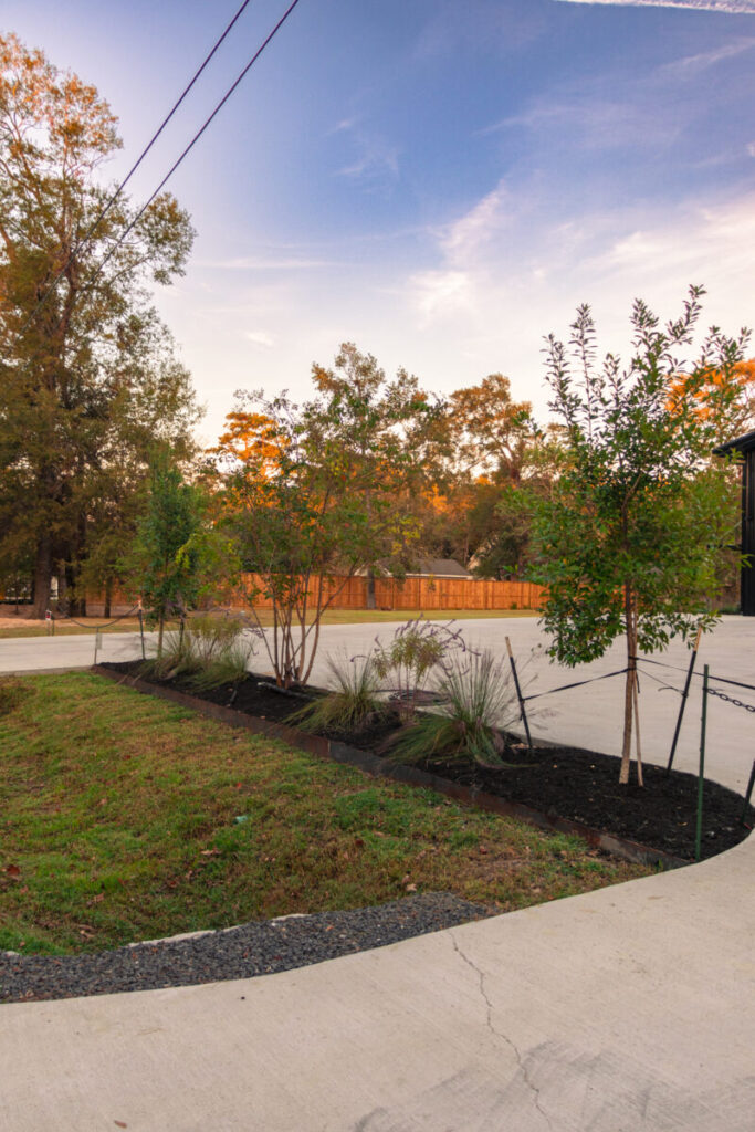 Houston Project - Acorn Ln - hardscaping, poured-in-place concrete pavers, black star gravel walkway, raised metal borders, artificial turf, low maintenance plants