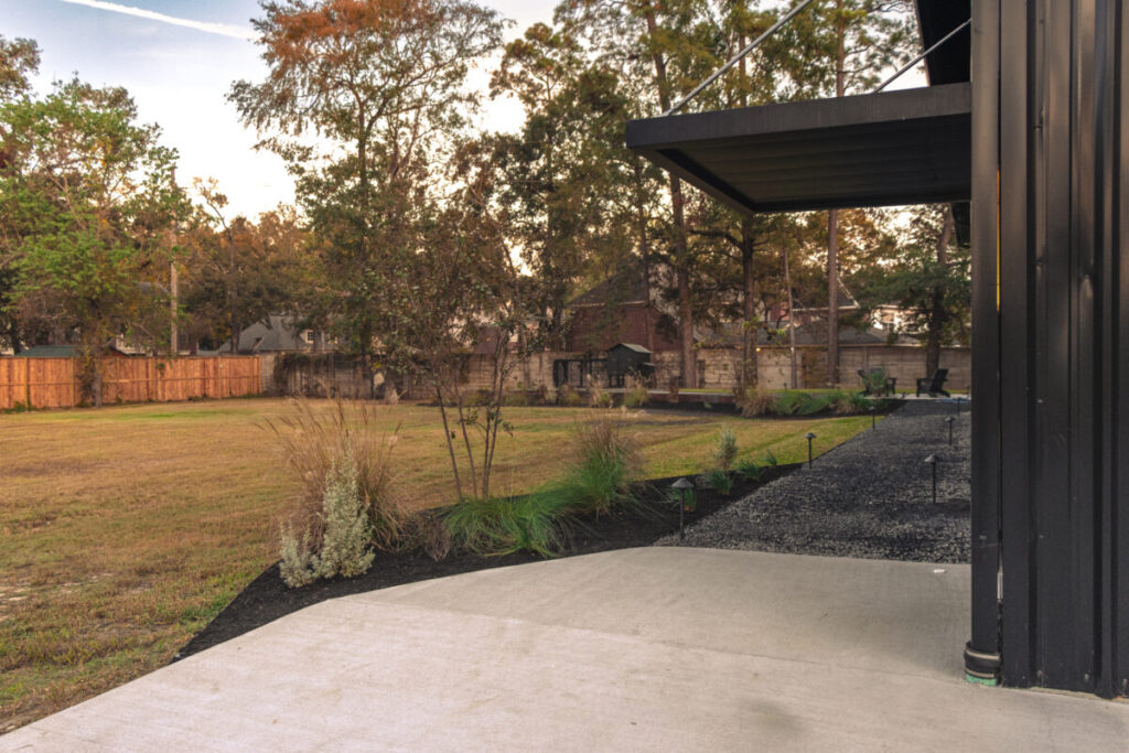 Houston Project - Acorn Ln - hardscaping, poured-in-place concrete pavers, black star gravel walkway, raised metal borders, artificial turf, low maintenance plants