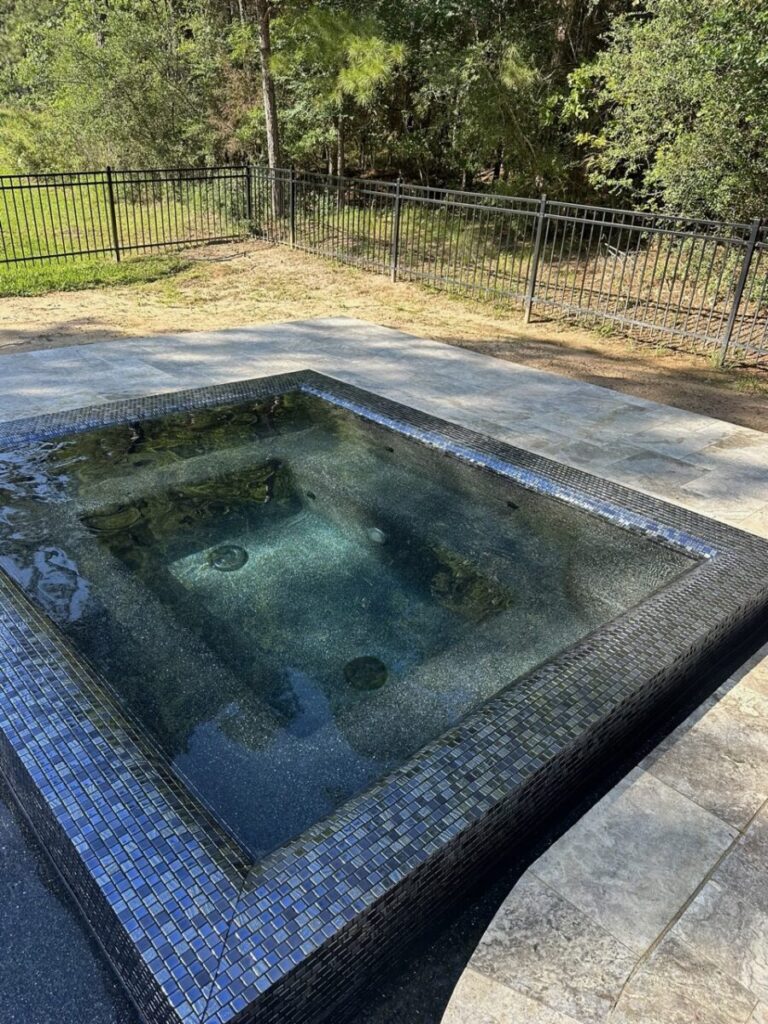 Magnolia Ranch Project - Roman-style pool with infinity edge spa, pillow-top edge, water features – three bubblers, six deck jets, French pattern travertine decking, chipping mat, artificial turf with putting green, accent boulders