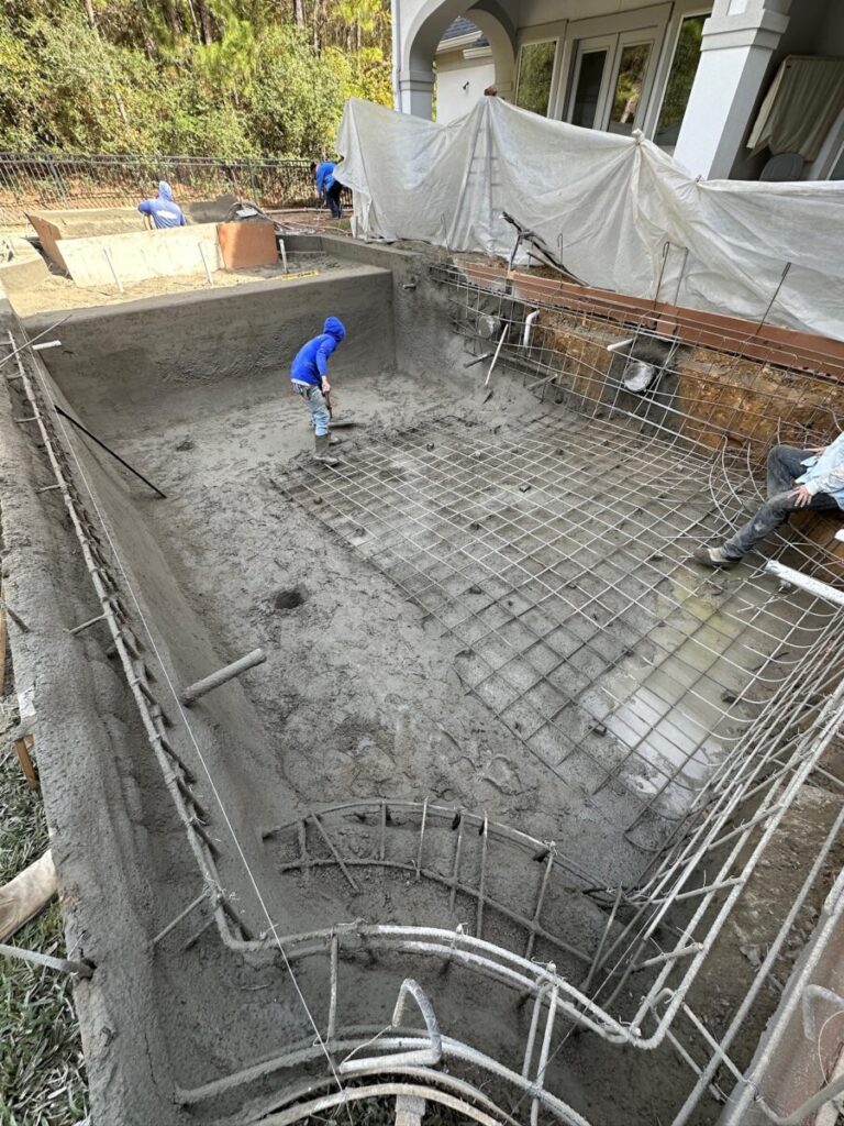 Magnolia Ranch Project - Roman-style pool with infinity edge spa, pillow-top edge, water features – three bubblers, six deck jets, French pattern travertine decking, chipping mat, artificial turf with putting green, accent boulders