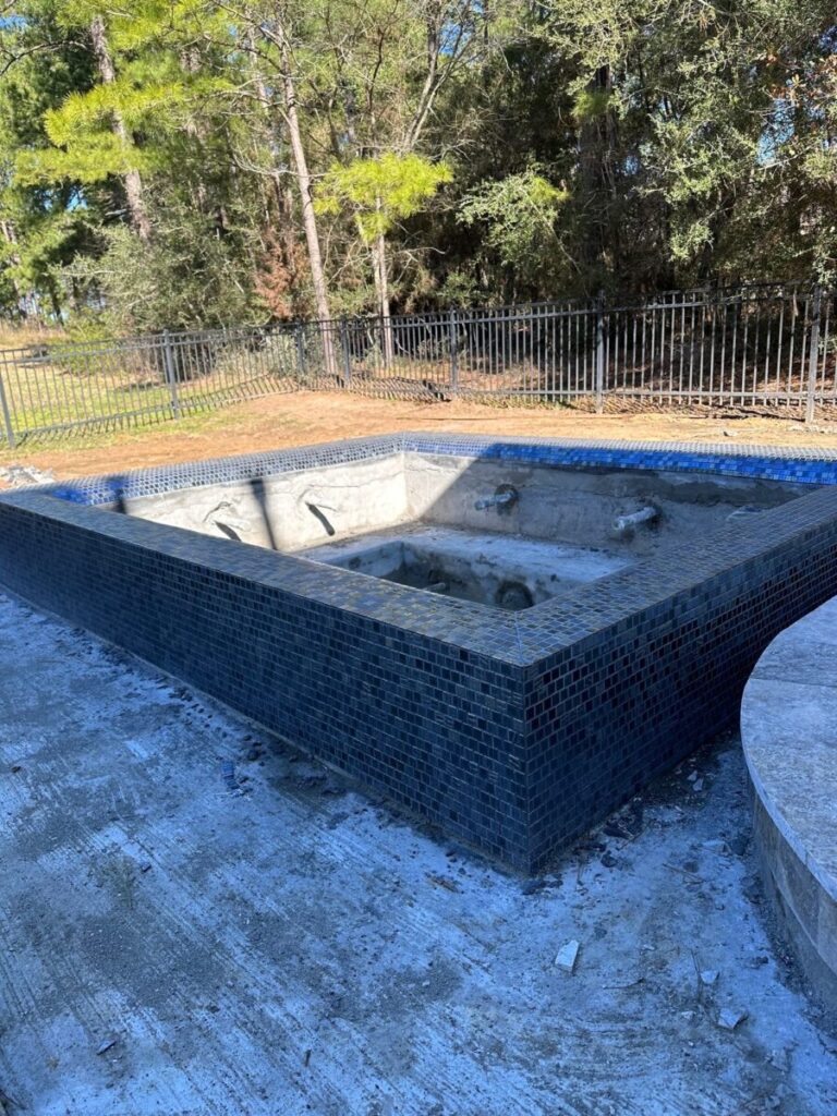 Magnolia Ranch Project - Roman-style pool with infinity edge spa, pillow-top edge, water features – three bubblers, six deck jets, French pattern travertine decking, chipping mat, artificial turf with putting green, accent boulders