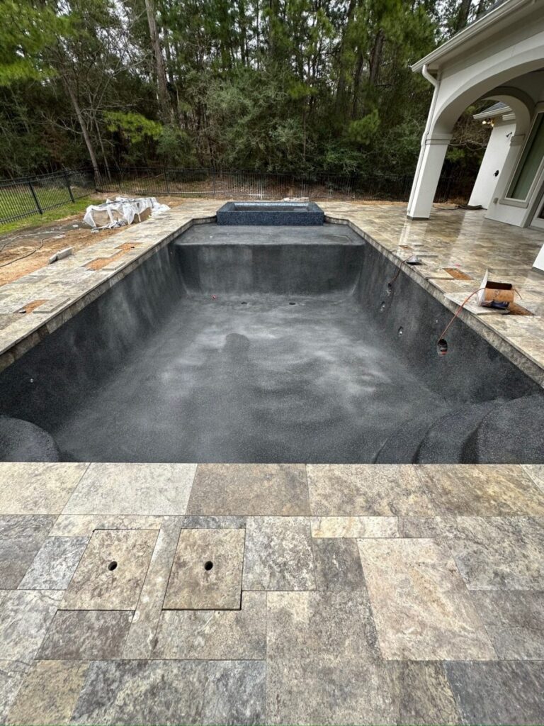 Magnolia Ranch Project - Roman-style pool with infinity edge spa, pillow-top edge, water features – three bubblers, six deck jets, French pattern travertine decking, chipping mat, artificial turf with putting green, accent boulders