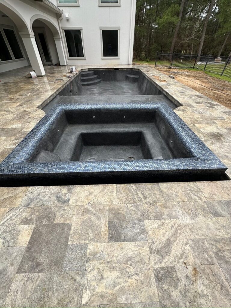 Magnolia Ranch Project - Roman-style pool with infinity edge spa, pillow-top edge, water features – three bubblers, six deck jets, French pattern travertine decking, chipping mat, artificial turf with putting green, accent boulders