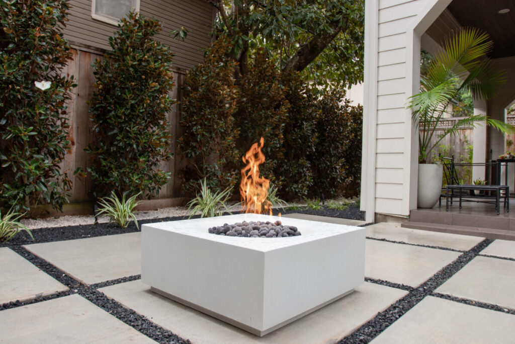 Heights Project Banks St - Poured-in-place concrete pavers, hardscaping, landscaping, Little Gem magnolia,, bamboo 'Graceful', Japanese yew, flax lily, black star gravel, white gravel, landscape uplights, Mexican heather, variegated liriope, sweet alyssum, metal planter, seasonal flowers, metal border built in-house, welded on-site, elegant white precast firepit