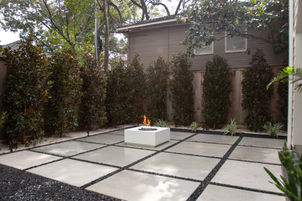 Heights Project Banks St - Poured-in-place concrete pavers, hardscaping, landscaping, Little Gem magnolia,, bamboo 'Graceful', Japanese yew, flax lily, black star gravel, white gravel, landscape uplights, Mexican heather, variegated liriope, sweet alyssum, metal planter, seasonal flowers, metal border built in-house, welded on-site, elegant white precast firepit