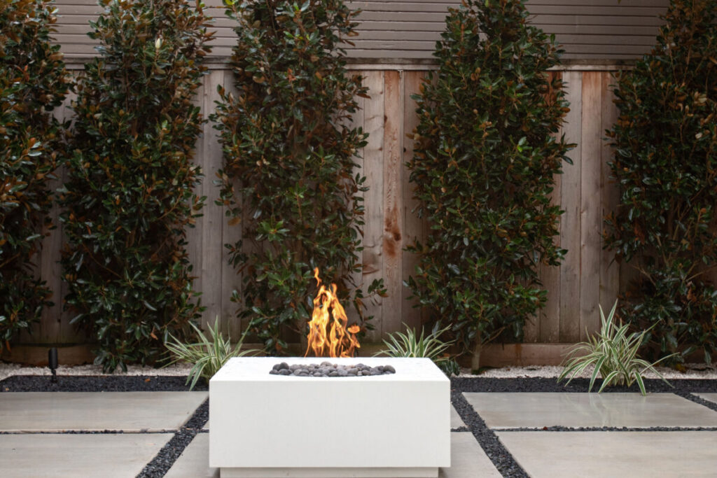 Heights Project Banks St - Poured-in-place concrete pavers, hardscaping, landscaping, Little Gem magnolia,, bamboo 'Graceful', Japanese yew, flax lily, black star gravel, white gravel, landscape uplights, Mexican heather, variegated liriope, sweet alyssum, metal planter, seasonal flowers, metal border built in-house, welded on-site, elegant white precast firepit