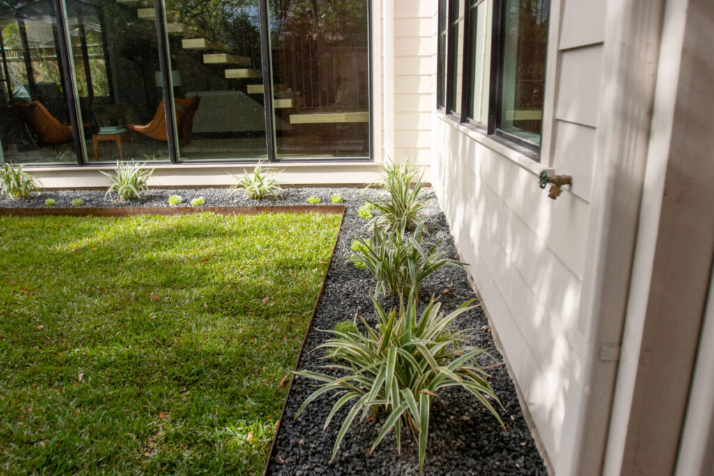 Heights Project Banks St - Poured-in-place concrete pavers, hardscaping, landscaping, Little Gem magnolia,, bamboo 'Graceful', Japanese yew, flax lily, black star gravel, white gravel, landscape uplights, Mexican heather, variegated liriope, sweet alyssum, metal planter, seasonal flowers, metal border built in-house, welded on-site, elegant white precast firepit