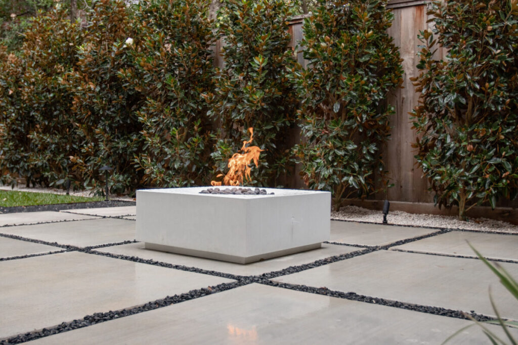 Heights Project Banks St - Poured-in-place concrete pavers, hardscaping, landscaping, Little Gem magnolia,, bamboo 'Graceful', Japanese yew, flax lily, black star gravel, white gravel, landscape uplights, Mexican heather, variegated liriope, sweet alyssum, metal planter, seasonal flowers, metal border built in-house, welded on-site, elegant white precast firepit