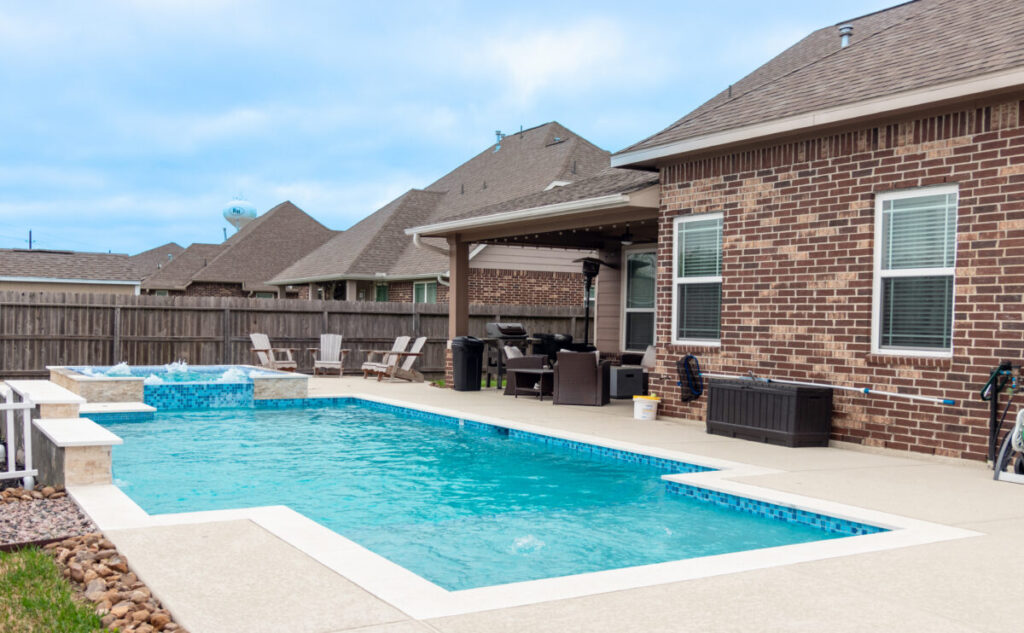 Mont Belvieu - Champions Gate - Geometric pool, raised spa, tanning ledge, water features - three scuppers and two bubblers, travertine coping, glass tile, pool table with travertine topper, raised backwall, spray decking, StoneScapes plaster