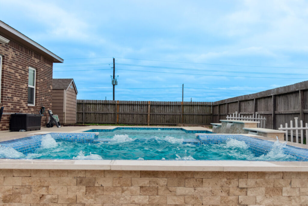 Mont Belvieu - Champions Gate - Geometric pool, raised spa, tanning ledge, water features - three scuppers and two bubblers, travertine coping, glass tile, pool table with travertine topper, raised backwall, spray decking, StoneScapes plaster