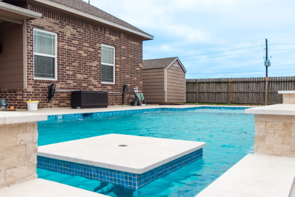 Mont Belvieu - Champions Gate - Geometric pool, raised spa, tanning ledge, water features - three scuppers and two bubblers, travertine coping, glass tile, pool table with travertine topper, raised backwall, spray decking, StoneScapes plaster