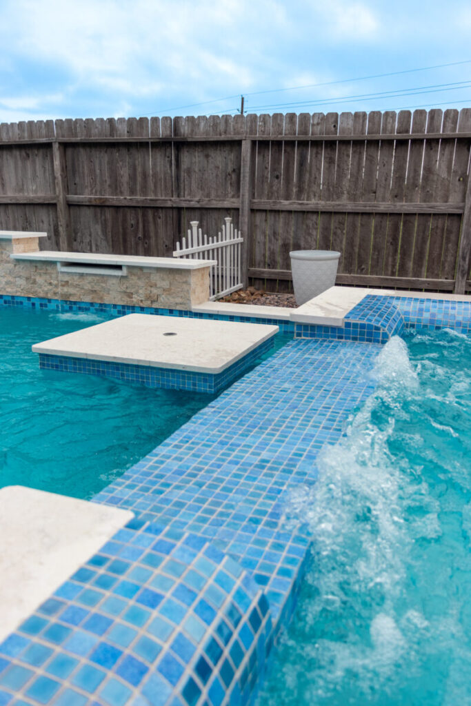 Mont Belvieu - Champions Gate - Geometric pool, raised spa, tanning ledge, water features - three scuppers and two bubblers, travertine coping, glass tile, pool table with travertine topper, raised backwall, spray decking, StoneScapes plaster