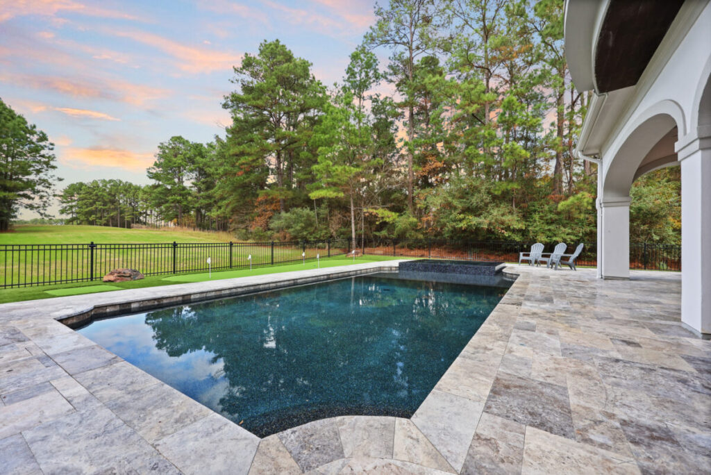 Magnolia Ranch Project - Roman-style pool with infinity edge spa, pillow-top edge, water features – three bubblers, six deck jets, French pattern travertine decking, chipping mat, artificial turf with putting green, accent boulders