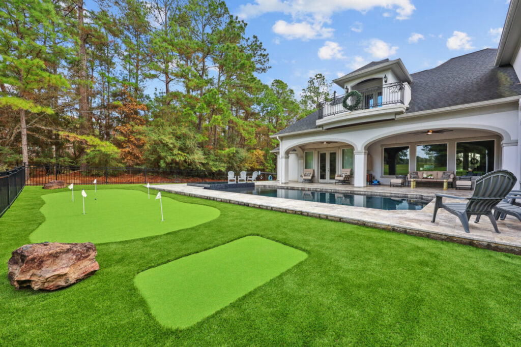 Magnolia Ranch Project - Roman-style pool with infinity edge spa, pillow-top edge, water features – three bubblers, six deck jets, French pattern travertine decking, chipping mat, artificial turf with putting green, accent boulders