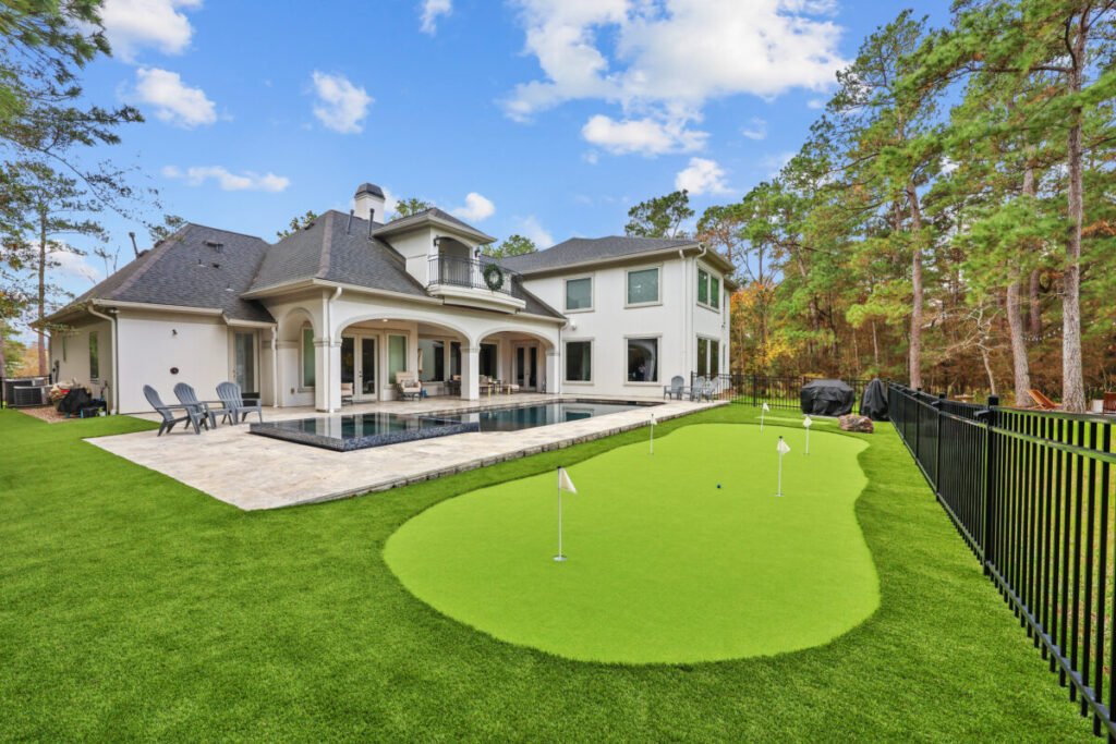 Magnolia Ranch Project - Roman-style pool with infinity edge spa, pillow-top edge, water features – three bubblers, six deck jets, French pattern travertine decking, chipping mat, artificial turf with putting green, accent boulders