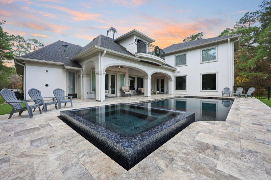 Magnolia Ranch Project - Roman-style pool with infinity edge spa, pillow-top edge, water features – three bubblers, six deck jets, French pattern travertine decking, chipping mat, artificial turf with putting green, accent boulders