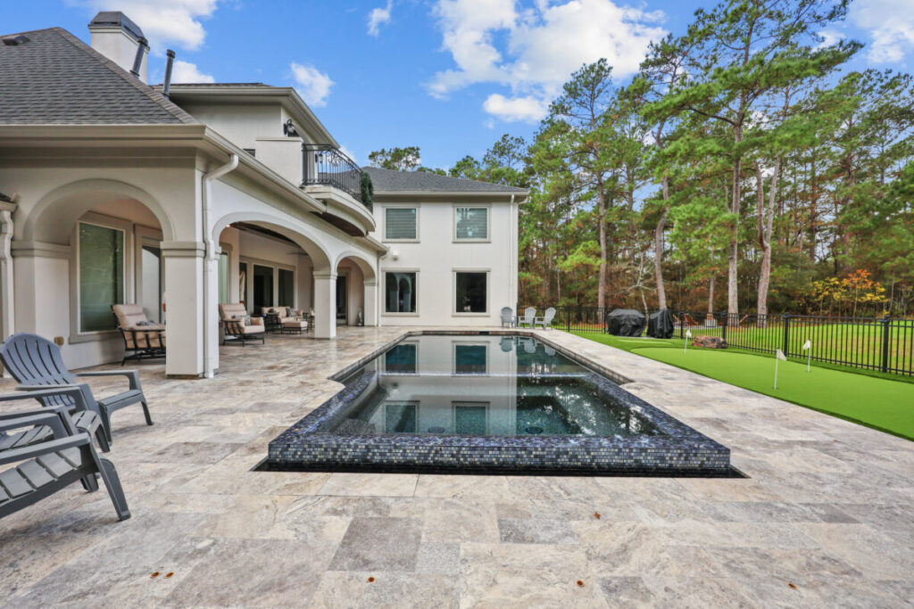 Magnolia Ranch Project - Roman-style pool with infinity edge spa, pillow-top edge, water features – three bubblers, six deck jets, French pattern travertine decking, chipping mat, artificial turf with putting green, accent boulders