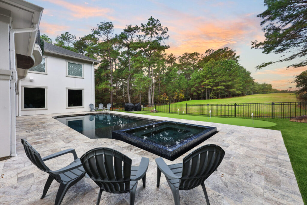 Magnolia Ranch Project - Roman-style pool with infinity edge spa, pillow-top edge, water features – three bubblers, six deck jets, French pattern travertine decking, chipping mat, artificial turf with putting green, accent boulders