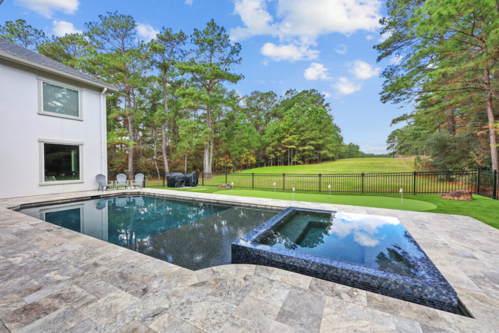 Magnolia Ranch Project - Roman-style pool with infinity edge spa, pillow-top edge, water features – three bubblers, six deck jets, French pattern travertine decking, chipping mat, artificial turf with putting green, accent boulders