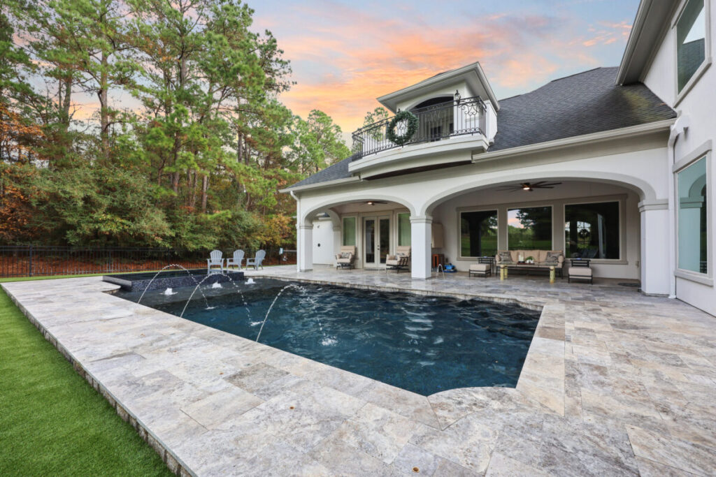 Magnolia Ranch Project - Roman-style pool with infinity edge spa, pillow-top edge, water features – three bubblers, six deck jets, French pattern travertine decking, chipping mat, artificial turf with putting green, accent boulders