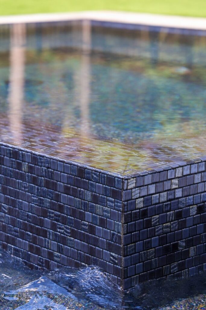 Magnolia Ranch Project - Roman-style pool with infinity edge spa, pillow-top edge, water features – three bubblers, six deck jets, French pattern travertine decking, chipping mat, artificial turf with putting green, accent boulders