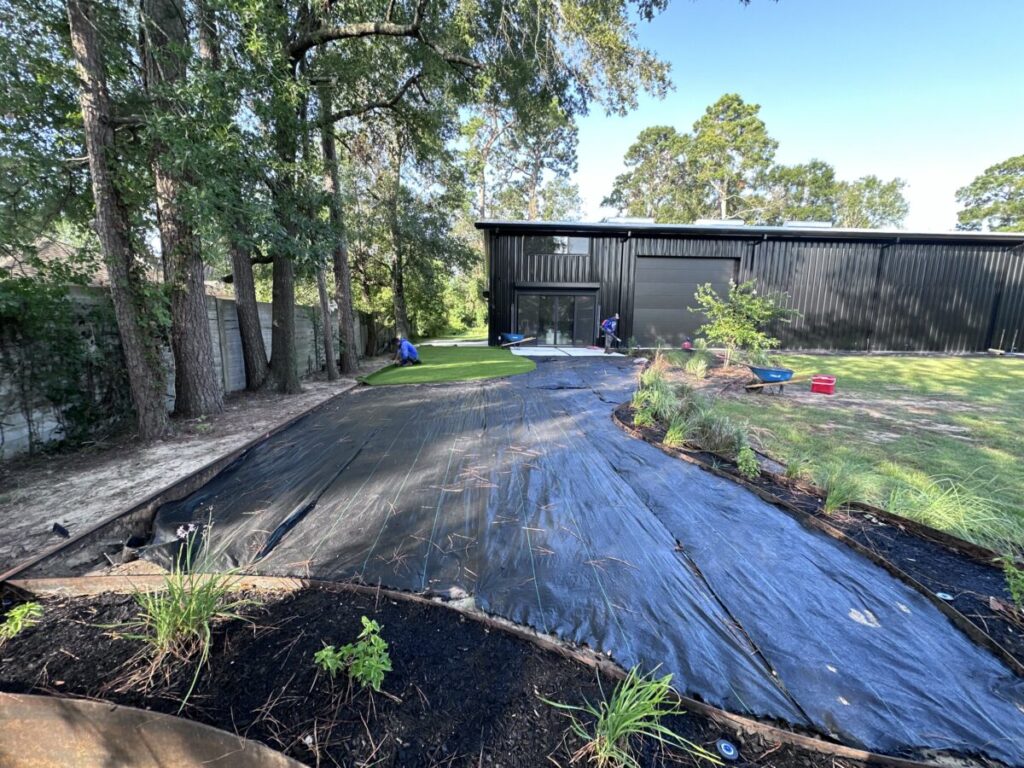 Houston Project - Acorn Ln - hardscaping, poured-in-place concrete pavers, black star gravel walkway, raised metal borders, artificial turf, low maintenance plants