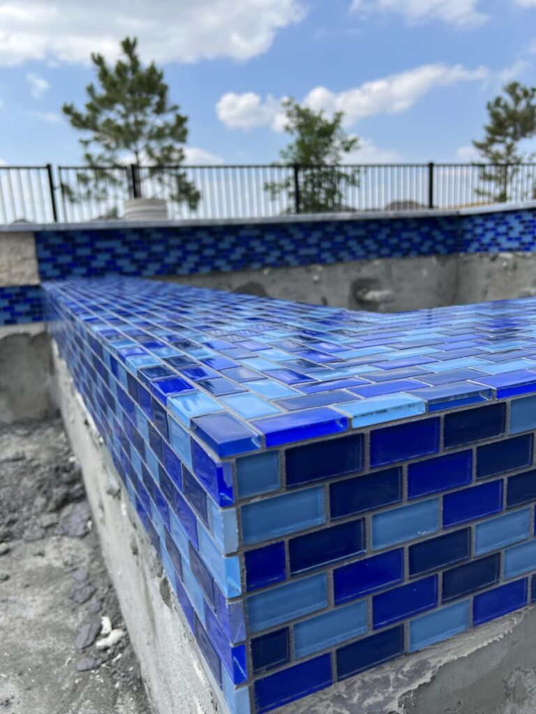 Cypress Project - Blue Wood - Geometric pool, tanning ledge, spa, safety railing, raised back wall, two fire bowls, one scupper, gas fire pit, multi-colored glass beads, travertine topper, split-face siding, glass tile, Arizona Sugar spray decking