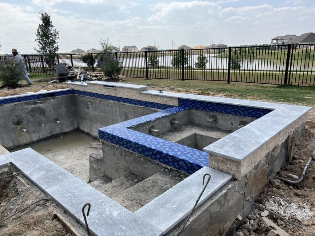 Cypress Project - Blue Wood - Geometric pool, tanning ledge, spa, safety railing, raised back wall, two fire bowls, one scupper, gas fire pit, multi-colored glass beads, travertine topper, split-face siding, glass tile, Arizona Sugar spray decking