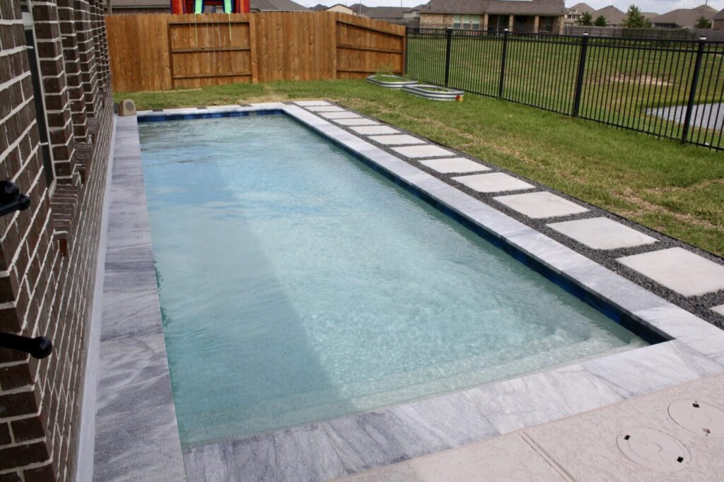 Texas Turf Tenders installed a geometric lap pool with a clean 6×6 tile finish. Spray decking offers a safe, polished surface, while a custom turf putting green finishes the minimal backyard makeover.